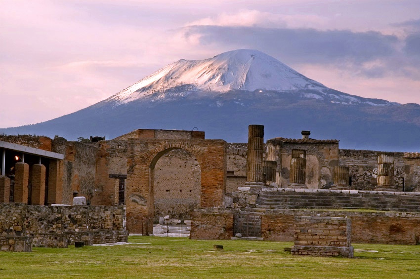 Ruinas de Pompeya en primer plano. El volcán, Vesubio, al fondo de la imagen.
